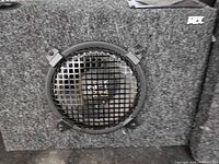 Front view of one MTX speaker showing woofer grille and carpeted cabinet