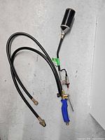 Full view of propane torch showing burner head, handle, hoses, and fittings