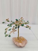 Front view of gemstone tree showing rose quartz base and wire branches with green and pink chips