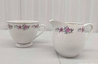 Teacup and matching creamer showing pattern and shape
