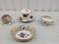 Group shot of teacup, saucer, landscape plate, reticulated bowl, creamer