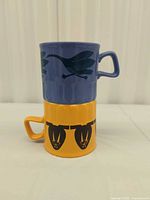 Stacked view of both mugs showing color and motifs