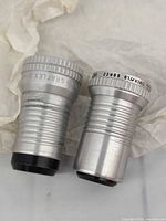 Two Somco silver aluminum lenses side by side, view of markings