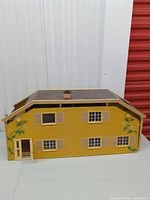 Front view of yellow Lundby dollhouse with brown roof, windows and door