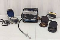 All items in lot laid out: camera in case, light meter, flash adapter, cable release, filters