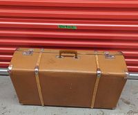 Front view closed suitcase showing handle, straps, corner guards and latches