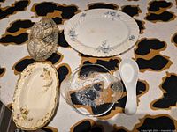 Top view of all five items laid out: platter, pressed glass dish, floral dish, etched glass bowl, ceramic spoon
