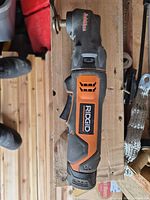 Side view of RIDGID 12V oscillating multi-tool lying on wooden surface