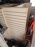 Vertical view of one light wood slatwall panel among storage items