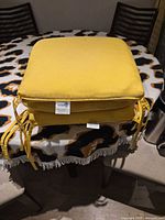 Stack of two yellow Sunbrella cushions on table showing color and ties