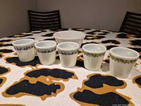 Five handled mugs and one bowl displayed on table