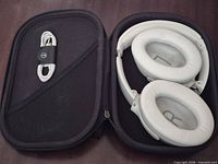 Headphones folded inside zip travel case with USB-C cable secured by strap