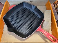 Top view of Le Creuset red square grill pan inside box, ridged interior visible