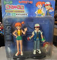 Front view of sealed blister pack showing Ash and Misty figures, branding and artwork
