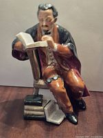 Front view of figurine showing professor reading, chair, books