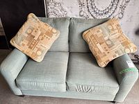 Front view of seafoam loveseat with two accent pillows