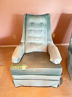 Front view of aqua velvet armchair showing tufted back, padded arms, skirted base