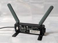 Rear view showing FCC label, dual gray antennae, attached USB cable
