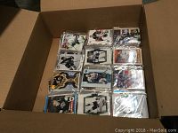 Box containing multiple packs of assorted NHL hockey cards, each pack has visible player cards inside plastic sleeves.