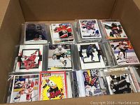 Box containing NHL hockey cards in plastic sleeves featuring various players and teams.