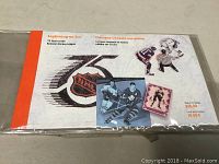 Front view of the sealed collector stamp booklet featuring NHL 75th anniversary graphics and some sample stamps.