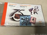 Front cover of NHL 75 Years stamp booklet showing 75th anniversary logo and hockey player images in plastic packaging.