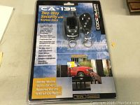 Front view of CA-135 two-way car security system and keyless entry package in blister pack with label and product visuals.