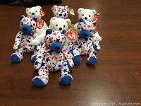Seven assorted Beanie Babies including five patriotic star-patterned bears and two white bears with red noses.