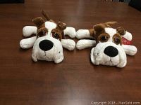 Two Russ Berrie plush dogs laid flat on a wooden table, showing front and back view, both in brown and white with floppy ears and large noses.