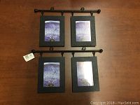 Two black metal bar hangers each holding two black vertical picture frames with placeholder images.