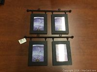 Two black metal bar hangers each holding two black rectangular picture frames with placeholder photos.