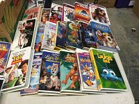 Photo showing a selection of VHS movies laid out on a floor, featuring titles like Toy Story 2, The Jungle Book 2, Lady and the Tramp, A Bug's Life, and others.