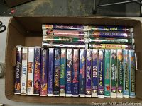 Box of assorted used VHS movies featuring titles primarily from Walt Disney such as Aladdin, The Fox and the Hound, Snow White, and Peter Pan.