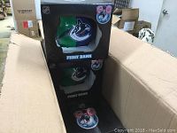 Photo showing boxes inside a shipping carton, each containing a Vancouver Canucks piggy bank in original packaging.