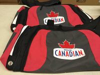 Two Molson Canadian branded duffel bags stacked on a table showcasing logo and design details.