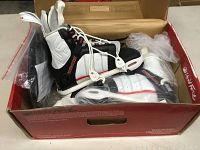 Wakeboard bindings inside a red Liquid Force box with plastic packaging and papers.