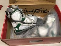 White and green wakeboard bindings in original packaging inside red box labeled Liquid Force.