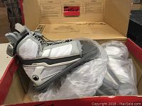 Photo of a pair of white and gray Liquid Force wakeboard bindings in original box with padding and straps visible.