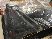 Liquid Force wakeboard bindings sealed in plastic inside original box showing the bindings' black and red color.