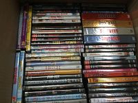 DVD collection tightly packed in a box, featuring titles such as The Sopranos, Friends, Sherlock Holmes, and others stacked side by side.