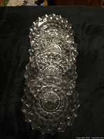 Four stacked clear glass plates displaying honeycomb pattern and scalloped rim