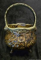 Front angle of embossed ceramic basket planter showing glaze and feet