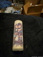 Full view of frosted cylindrical votive candle holder showing child illustration and wear