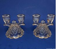 Pair of clear pressed glass double light candlestick holders on blue background