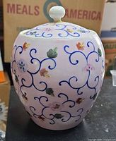 Front view of pink porcelain ginger jar with lid showing hand-painted floral and scrollwork decoration
