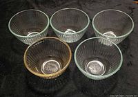 Five ribbed glass bowls, four blue/green, one pink/amber, viewed from top