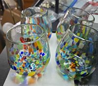Four multicolor speckled stemless wine glasses on tabletop
