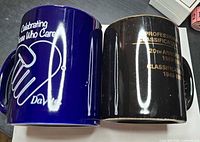Cobalt blue DaVita mug beside black Professional Classification mug