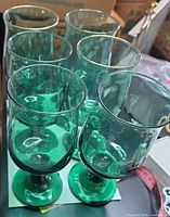 Six green glass goblets grouped; two show gold rim