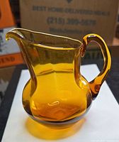 Front view of amber glass mini pitcher showing handle and spout